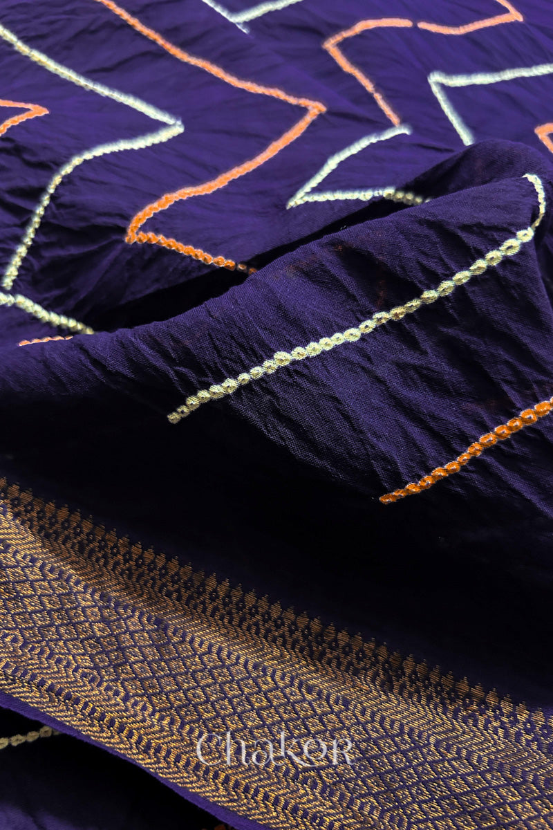 Close-up of Purple sarees featuring rai bandhani and zari weaving showcasing beautiful craftsmanship.
