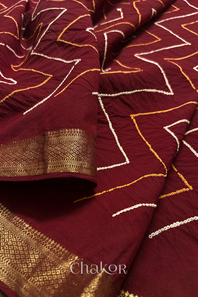 Close-up of Red sarees featuring rai bandhani and zari weaving showcasing beautiful craftsmanship.
