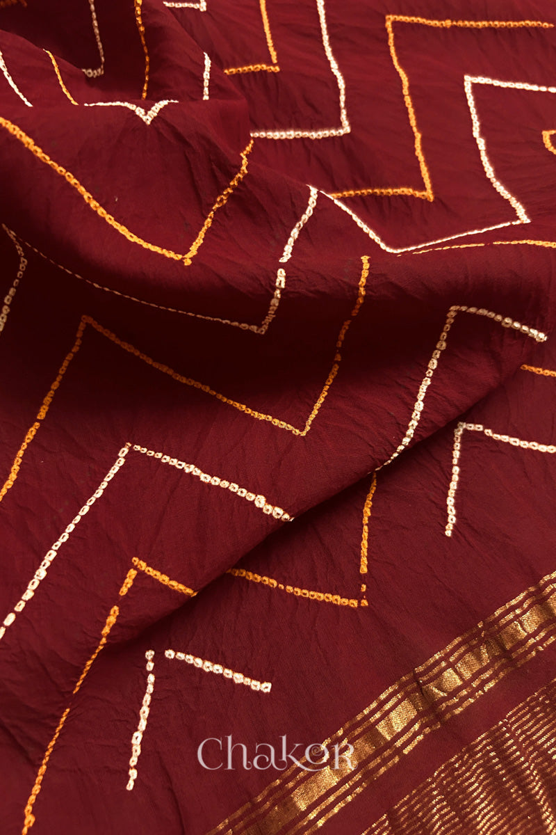 Close-up of Red sarees featuring rai bandhani in zig-zag pattern 
and zari weaving showcasing beautiful craftsmanship.
