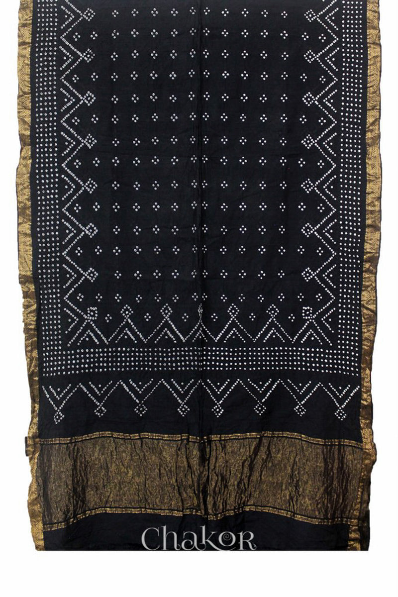 Black saree, flat draped with Rai Bandhej traditional design against white background and 'Chakor' watermark.
