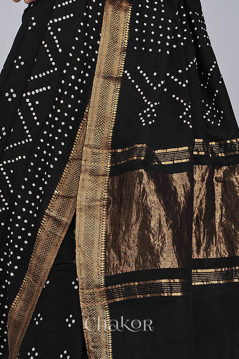 Close-up of black saree with rai bandhej pallu and golden border showcasing intricate tie-dye craftsmanship.

