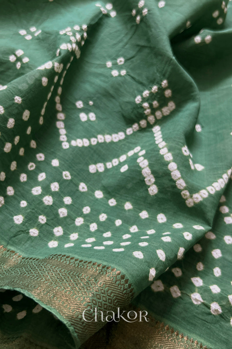 Close-up of moss green saree with rai bandhej showcasing intricate tie-dye craftsmanship and fabric texture.
