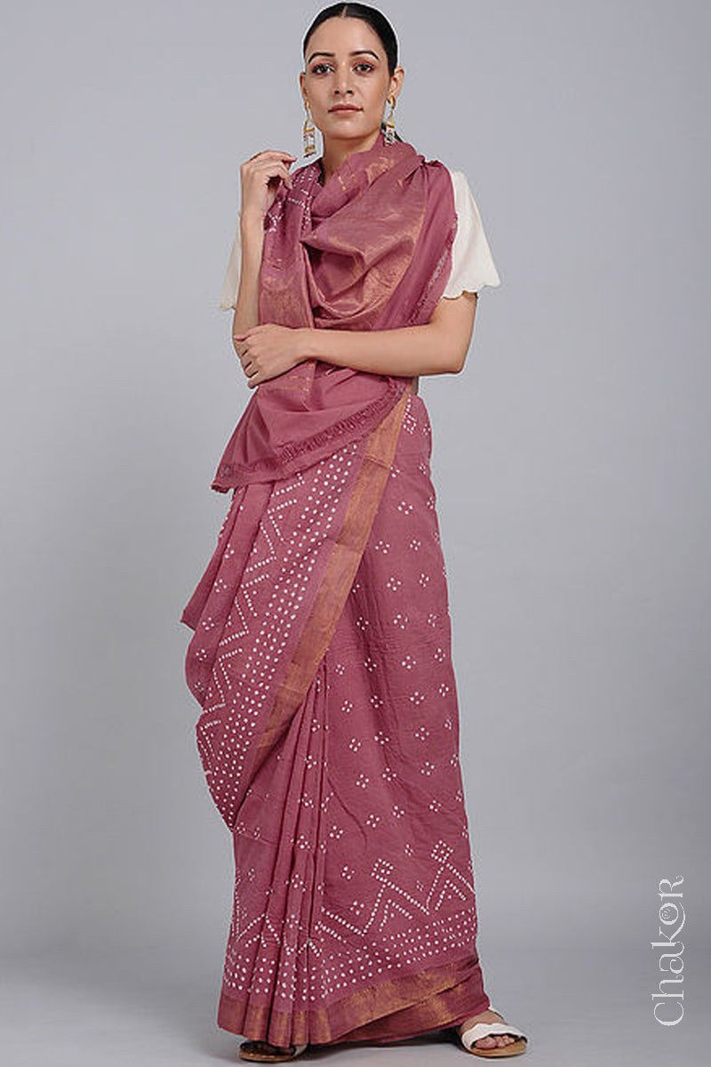 Woman wearing a old rose saree with white bandhani designs, featuring golden zari borders. 