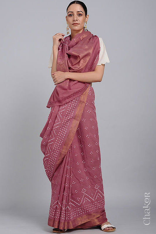 Woman wearing a old rose saree with white bandhani designs, featuring golden zari borders. 