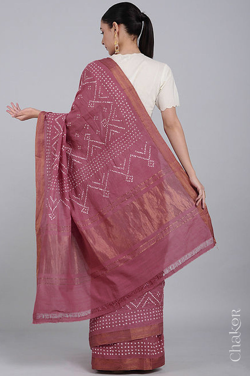 Woman wearing a old rose saree with white bandhani designs, showcasing golden pallu and zari borders.