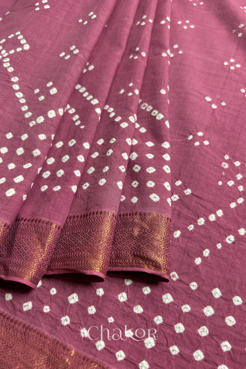 Close-up of old rose saree, arranged in pleats with rai bandhani and golden border showcasing beautiful craftsmanship.
