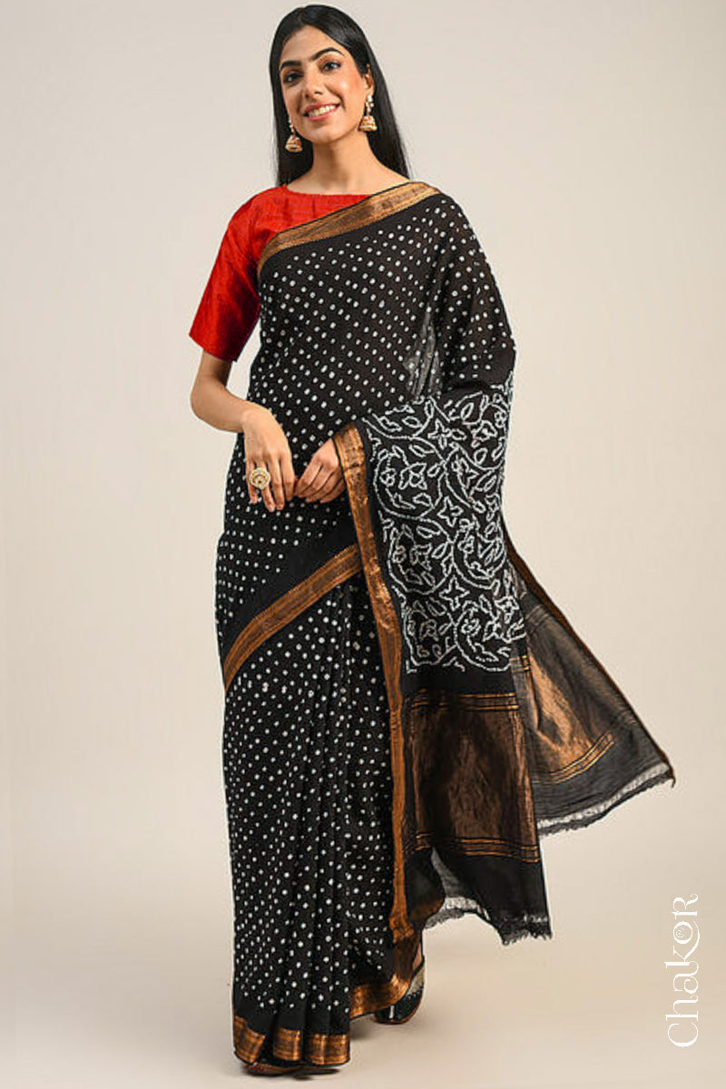 Woman wearing a black bandhani saree with traditional bandhej designs and zari border pallu.