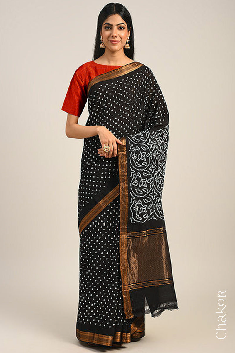 Woman wearing a black bandhani saree with traditional bandhej designs and zari border pallu.