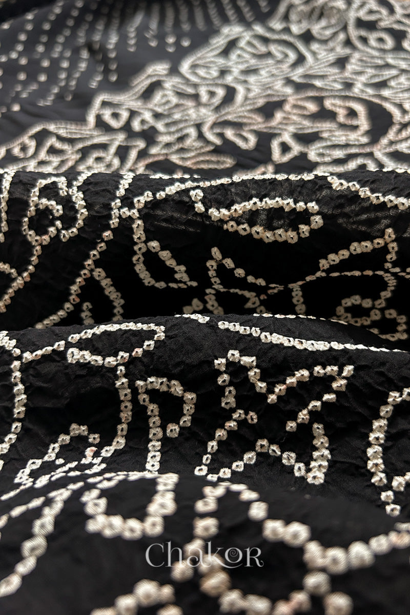 Close-up of black saree with rai bandhej showcasing intricate tie-dye craftsmanship.
