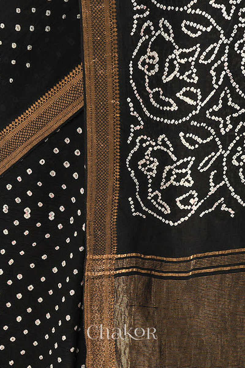 Close-up of black saree with rai bandhej pallu and golden border showcasing intricate tie-dye craftsmanship.
