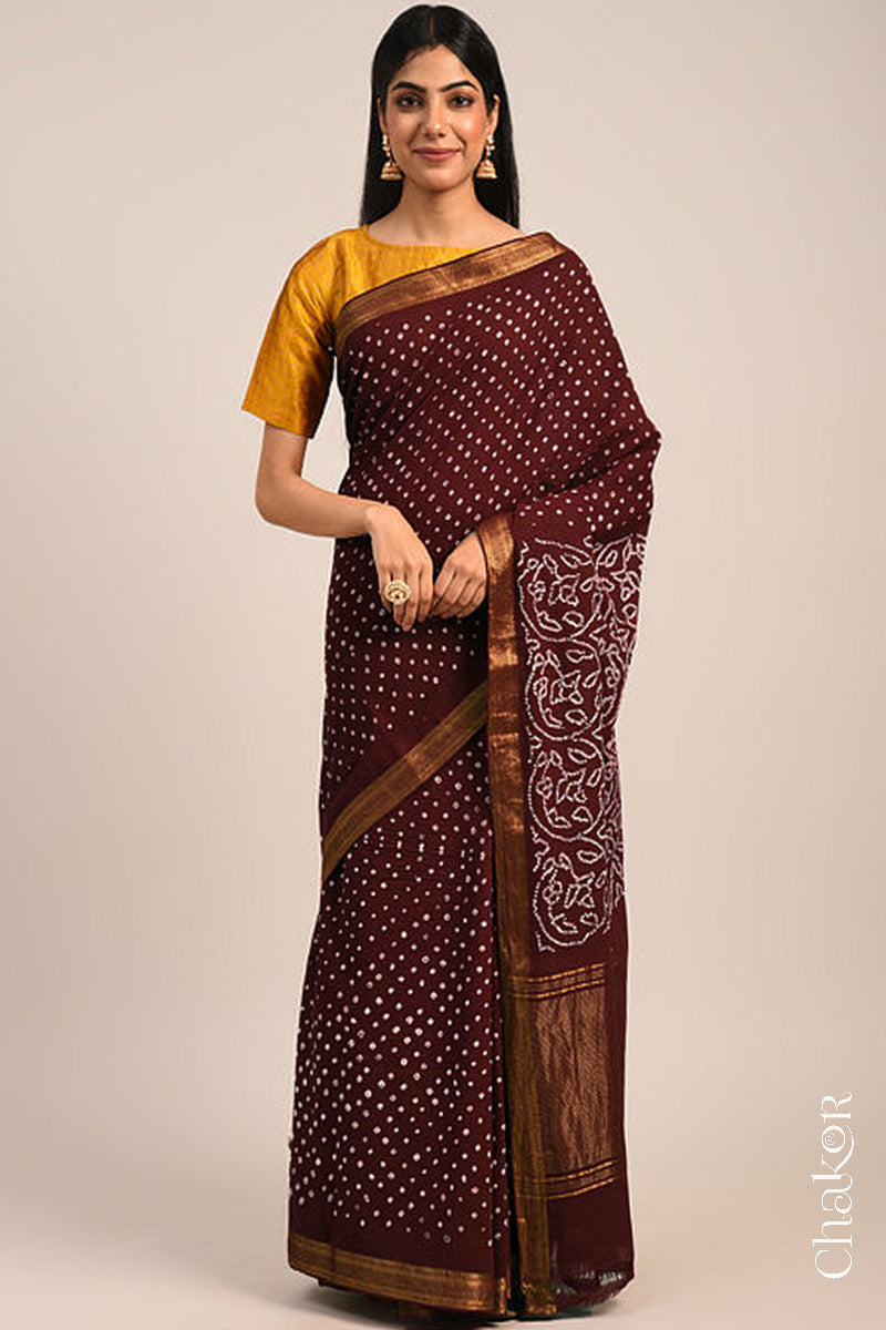 Woman wearing a maroon bandhani saree with traditional bandhej designs and zari border pallu.