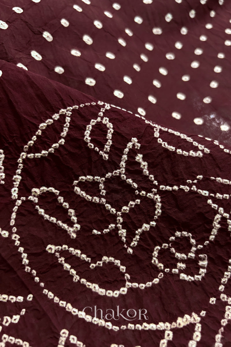 Close-up of maroon saree with rai bandhej showcasing intricate tie-dye craftsmanship and fabric texture.
