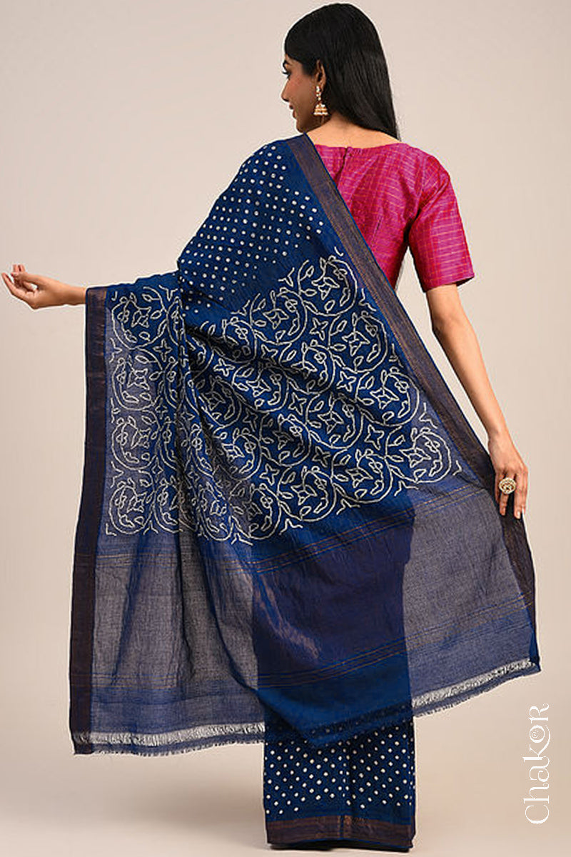 Woman wearing a navy blue bandhani saree showcasing intricate tie dye design on pallu and zari border.