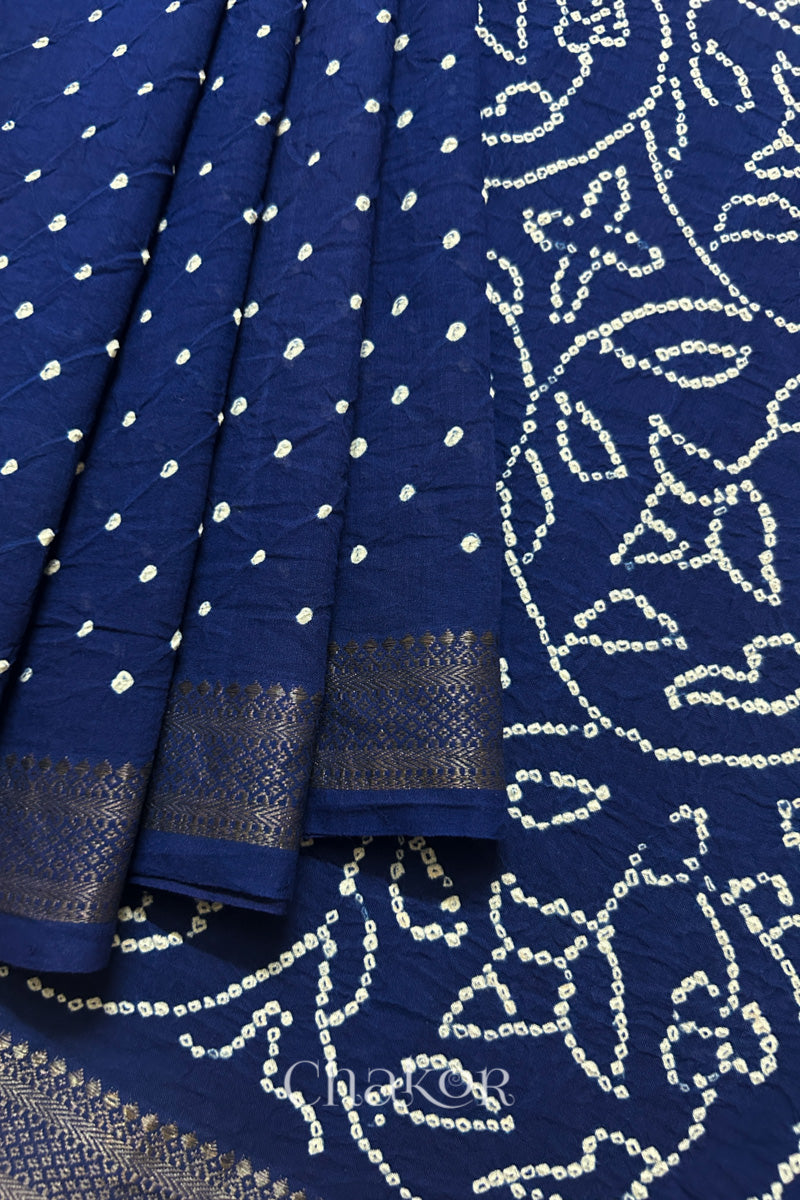 Close-up of navy blue saree, arranged in pleats with rai bandhani and dull golden border showcasing beautiful craftsmanship.
