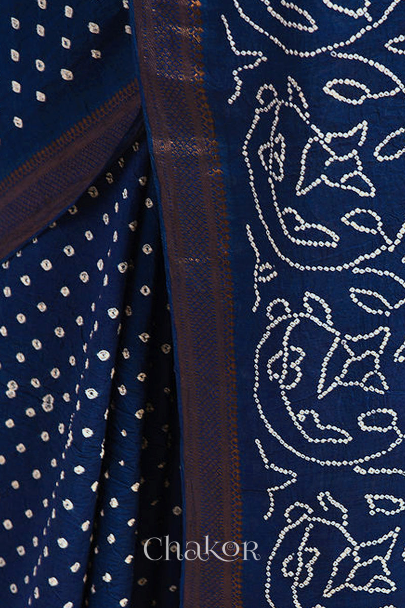 Close-up of navy blue saree with rai bandhej pallu and dull golden border showcasing intricate tie-dye craftsmanship.
