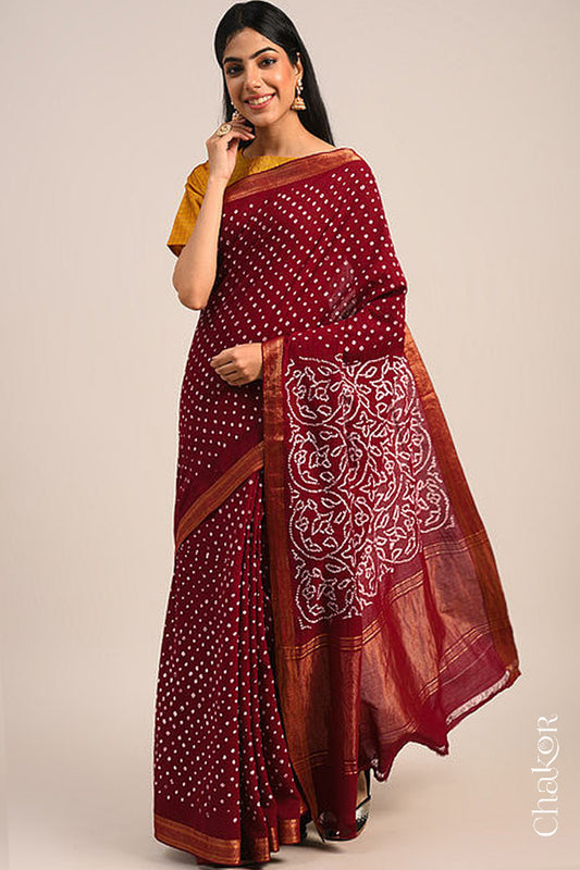 Woman wearing a red bandhani saree with traditional bandhej designs and zari border pallu.
