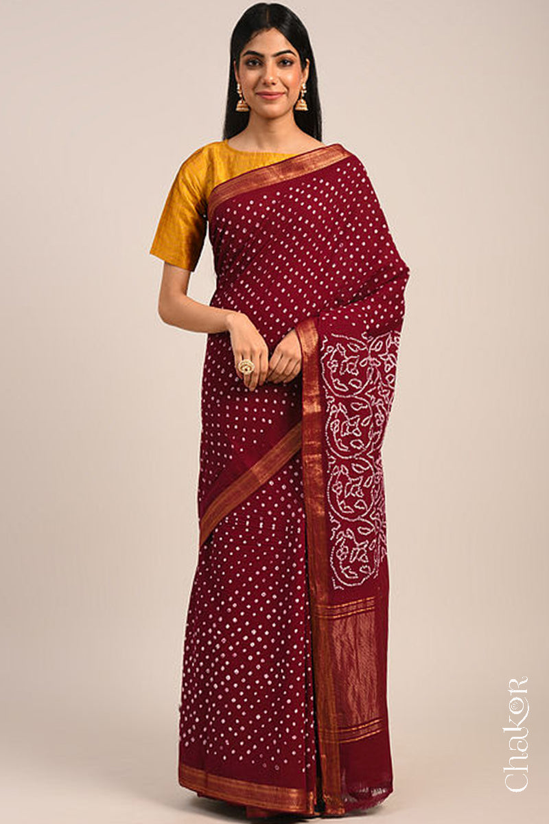 Woman wearing a red bandhani saree with traditional bandhej designs and zari border pallu.