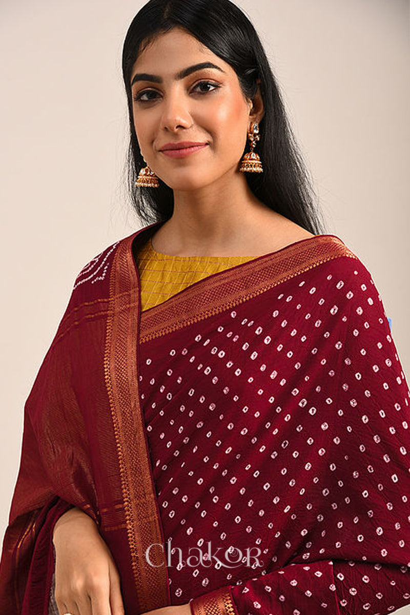 Woman wearing a red bandhej saree with white bandhani dots and golden border.