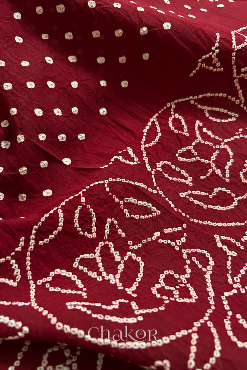 Close-up of red saree with rai bandhej showcasing intricate tie-dye craftsmanship.
