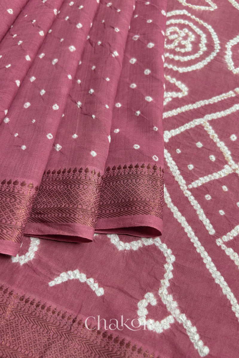 Close-up of Old rose saree, arranged in pleats with rai bandhani and golden border showcasing beautiful craftsmanship.
