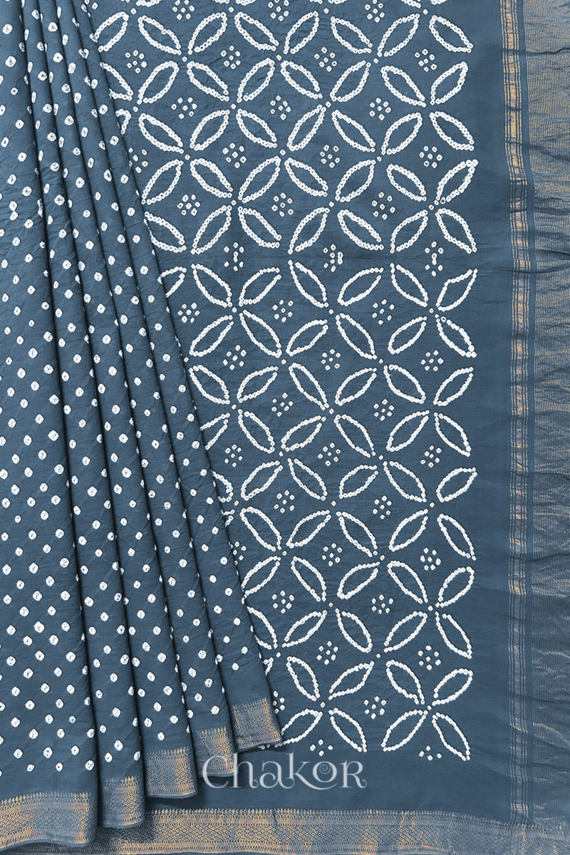 Grey saree, neatly arranged in pleats with Rai Bandhej traditional design and 'Chakor' brand watermark.
