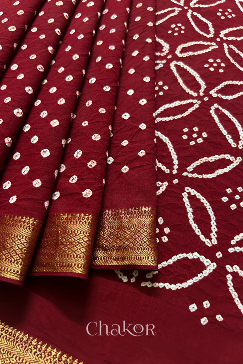 Close-up of Red saree, arranged in pleats with rai bandhani and golden border showcasing beautiful craftsmanship.
