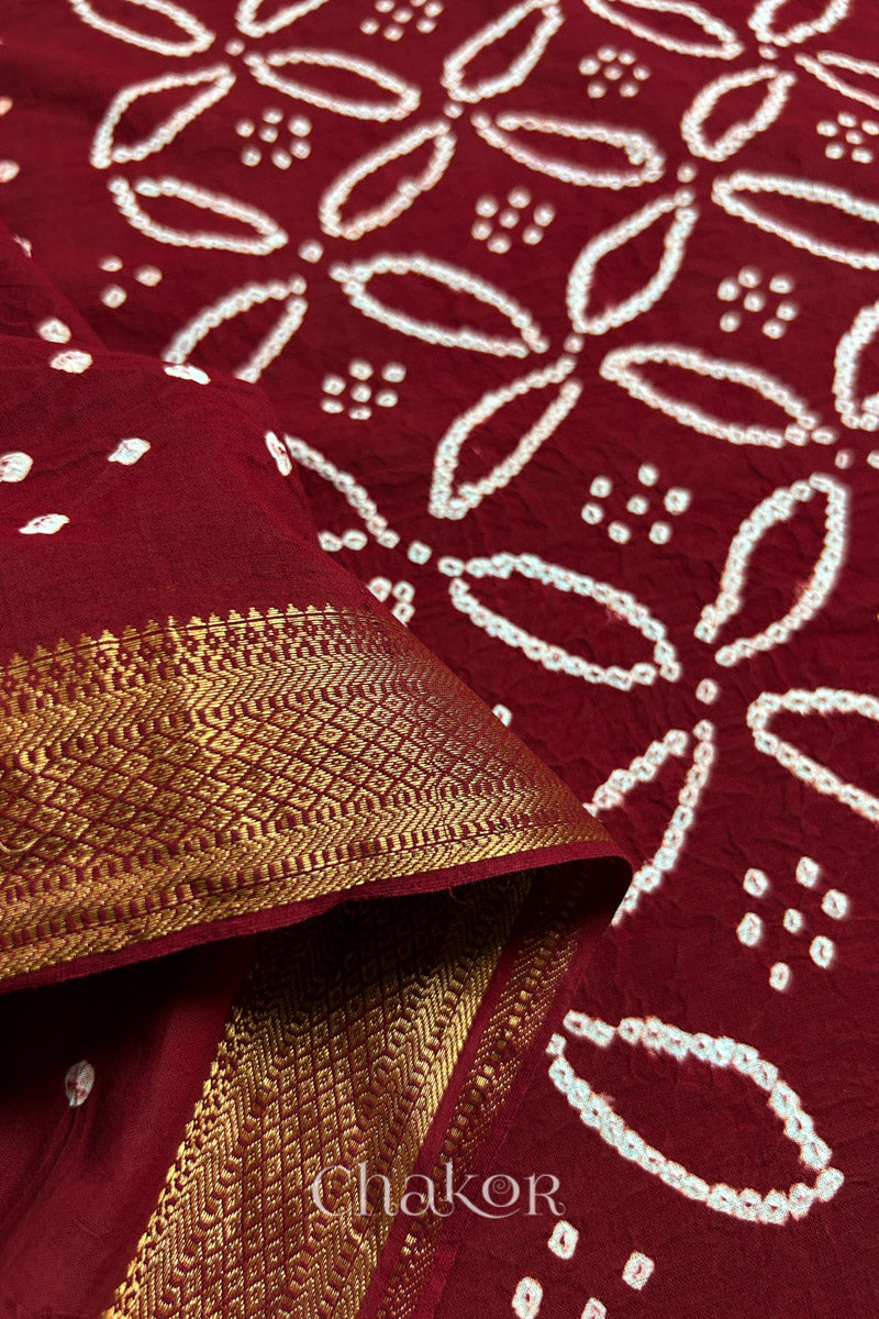 Close-up of Red sarees featuring rai bandhani and zari weaving showcasing beautiful craftsmanship.
