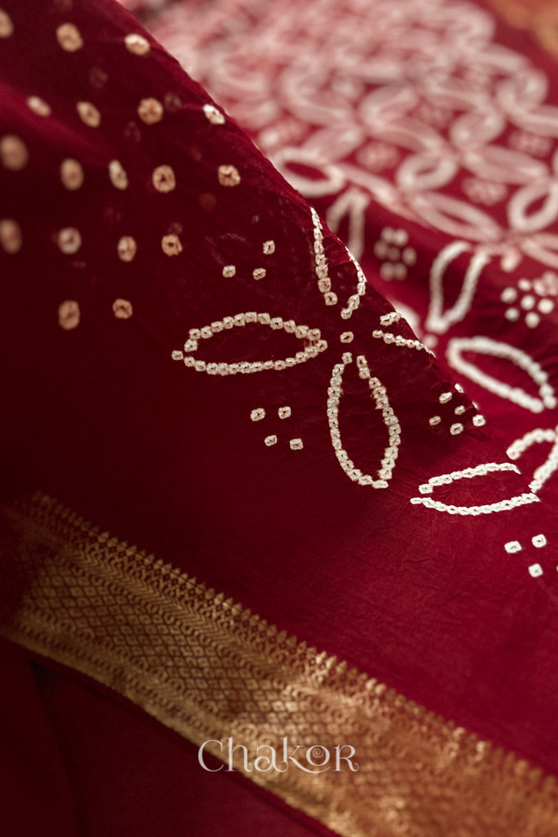Close-up of Red sarees featuring rai bandhani and zari weaving showcasing beautiful craftsmanship.
