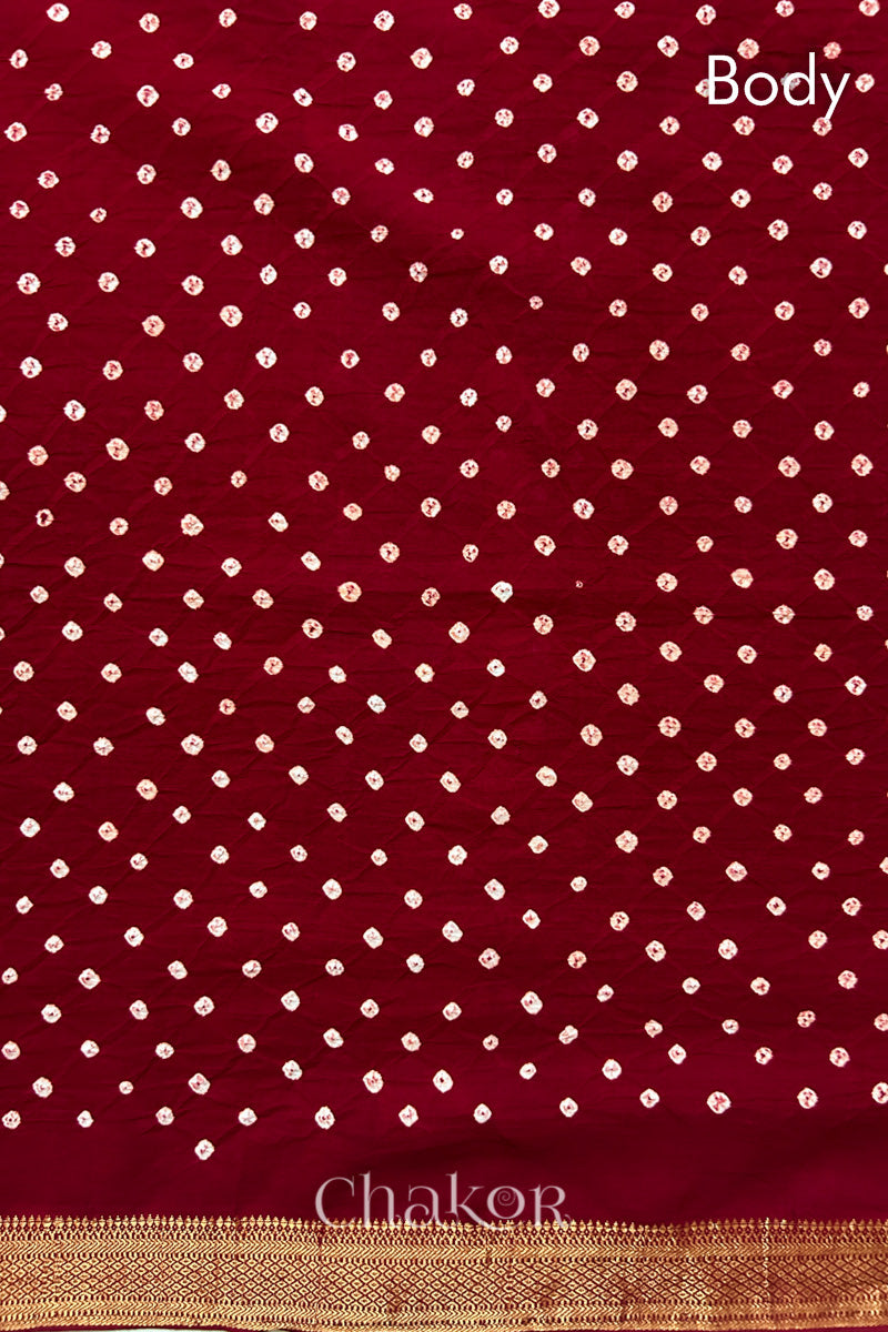 Body detail of Red bandhani saree with woven golden zari border.
