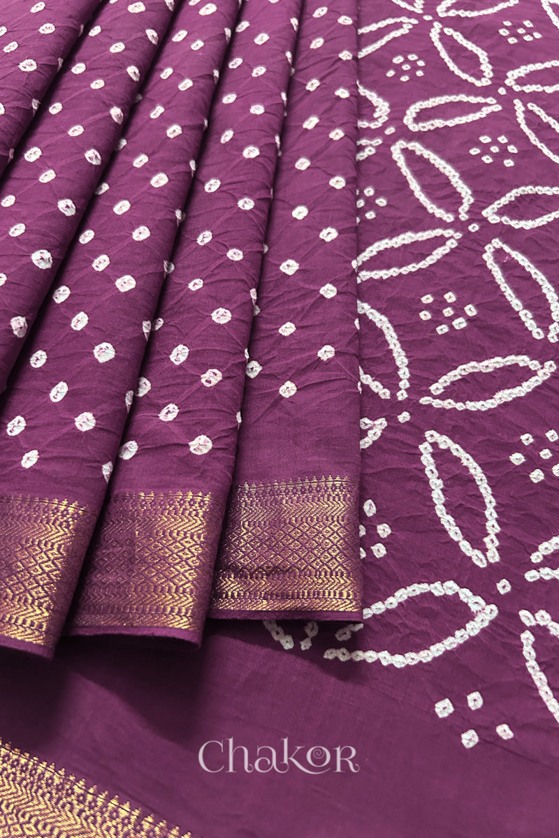 Close-up of Purple saree, arranged in pleats with rai bandhani and golden border showcasing beautiful craftsmanship.
