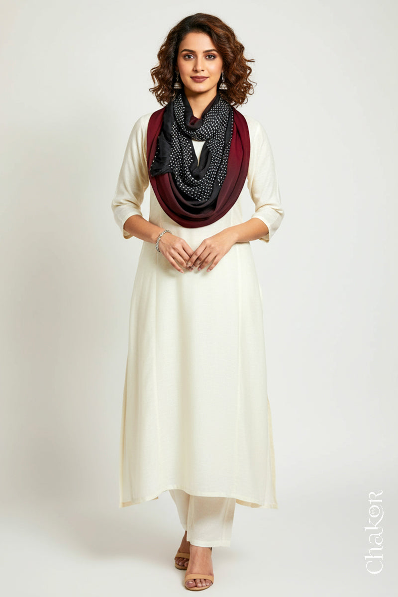 Woman wearing a maroon black shaded bandhani scarf  on white kurta set.
