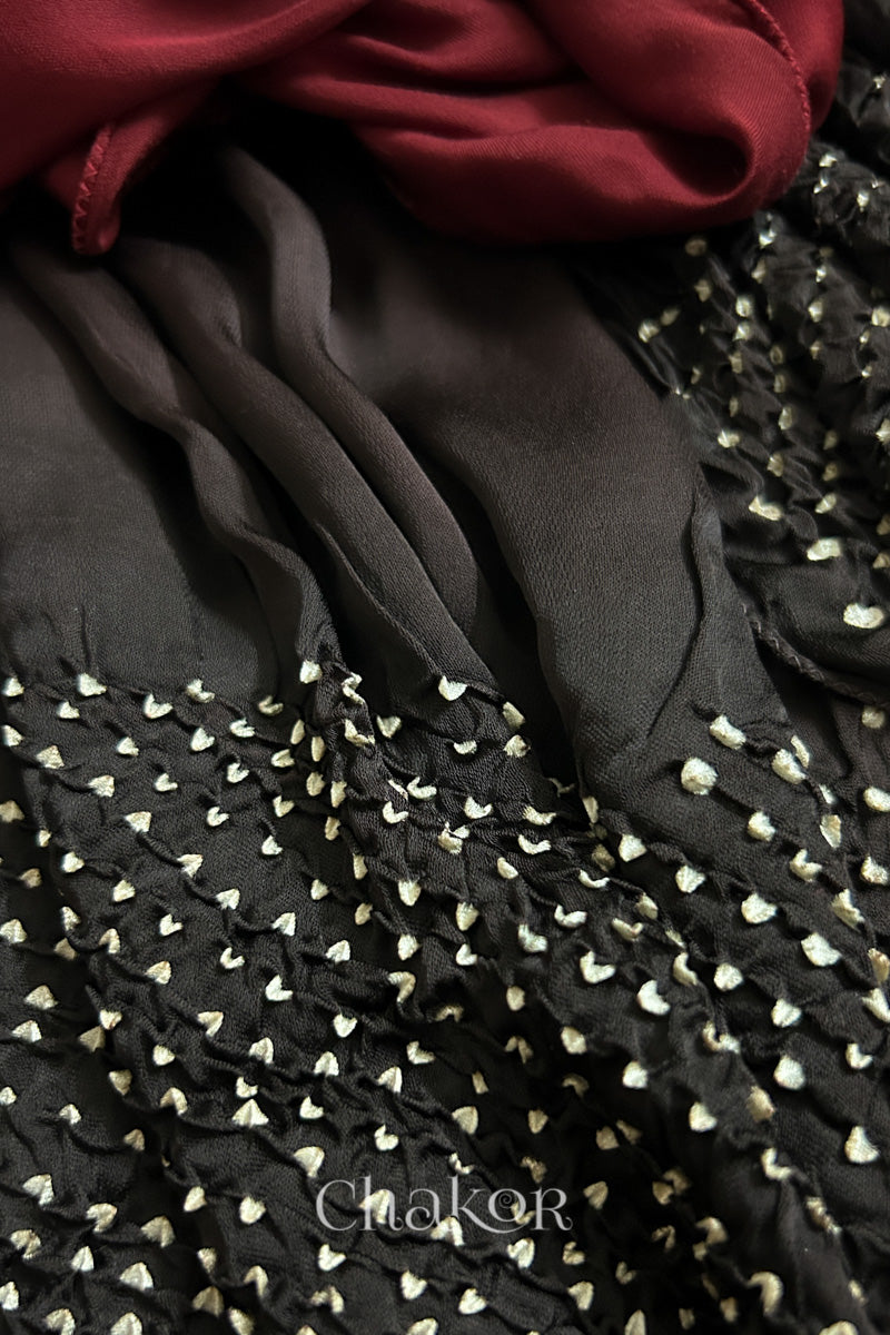 Close-up of bandhani stole featuring ombre dyeing in maroon & black and  intricate tie dye patterns with 'Chakor' branding.