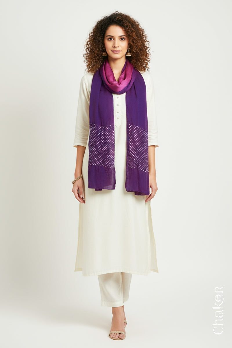 Woman wearing a magenta & purple shaded bandhani stole on white kurta set.
