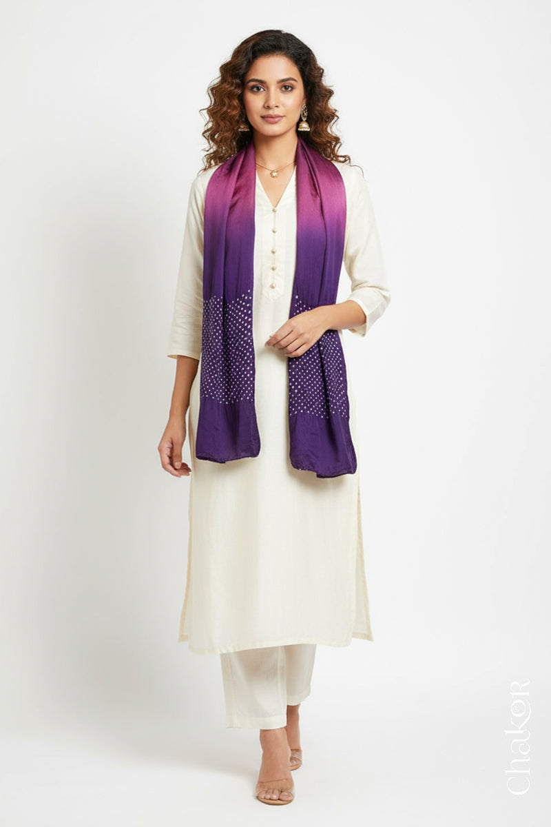 Woman wearing a magenta & purple shaded bandhani stole on white kurta set.
