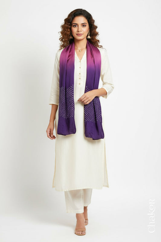 Woman wearing a magenta & purple shaded bandhani stole on white kurta set.
