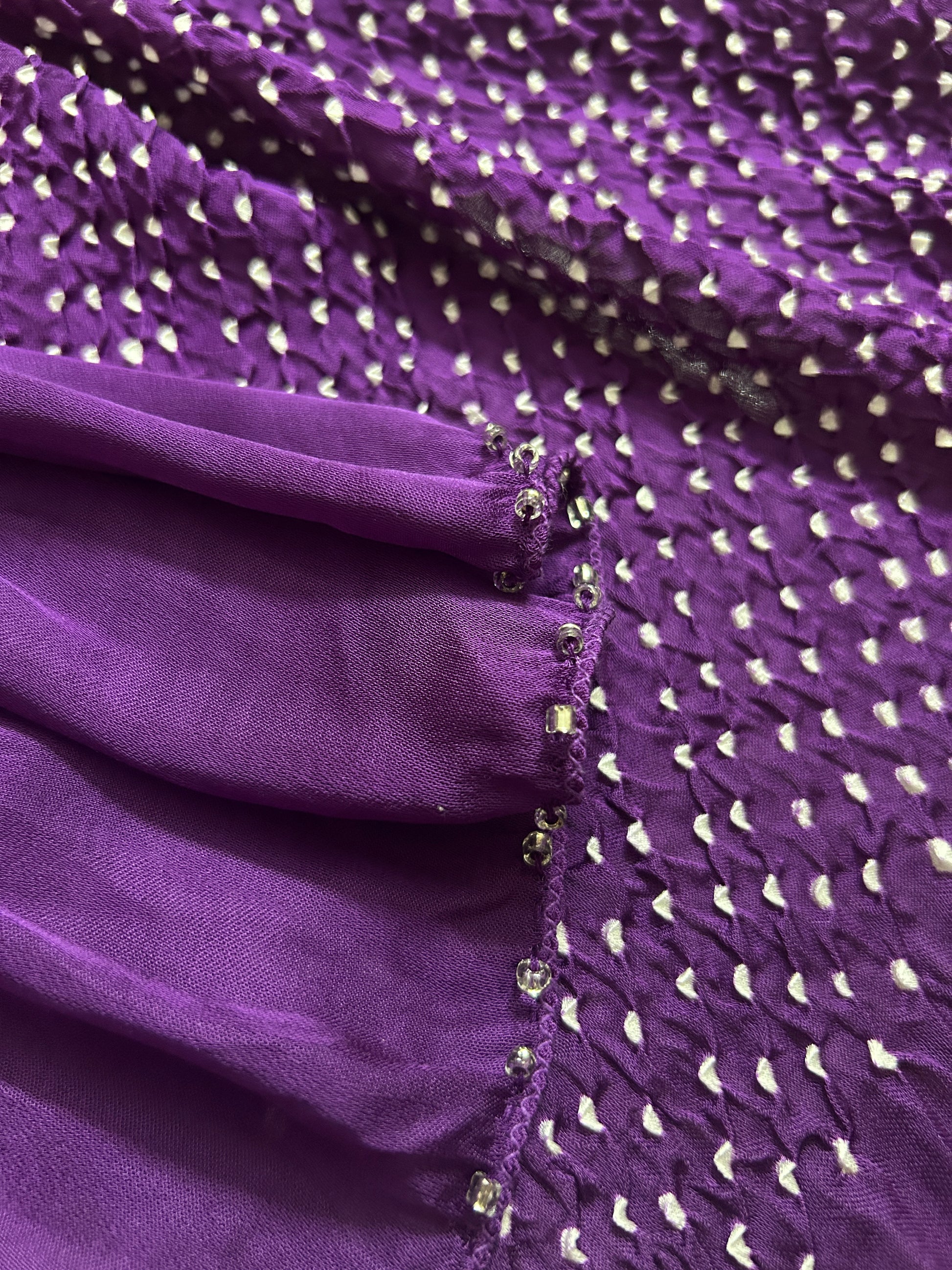 Close-up of bandhani stole featuring ombre dyeing in magenta & purple and  intricate tie dye patterns with 'Chakor' branding.
