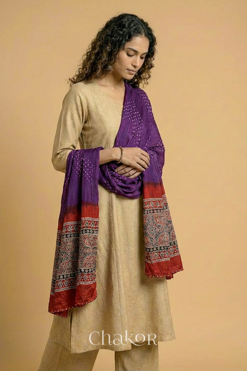Purple Bandhani modal stole styled across shoulders with detailed Madder Red Ajrakh pallu and traditional hand tied pattern.
