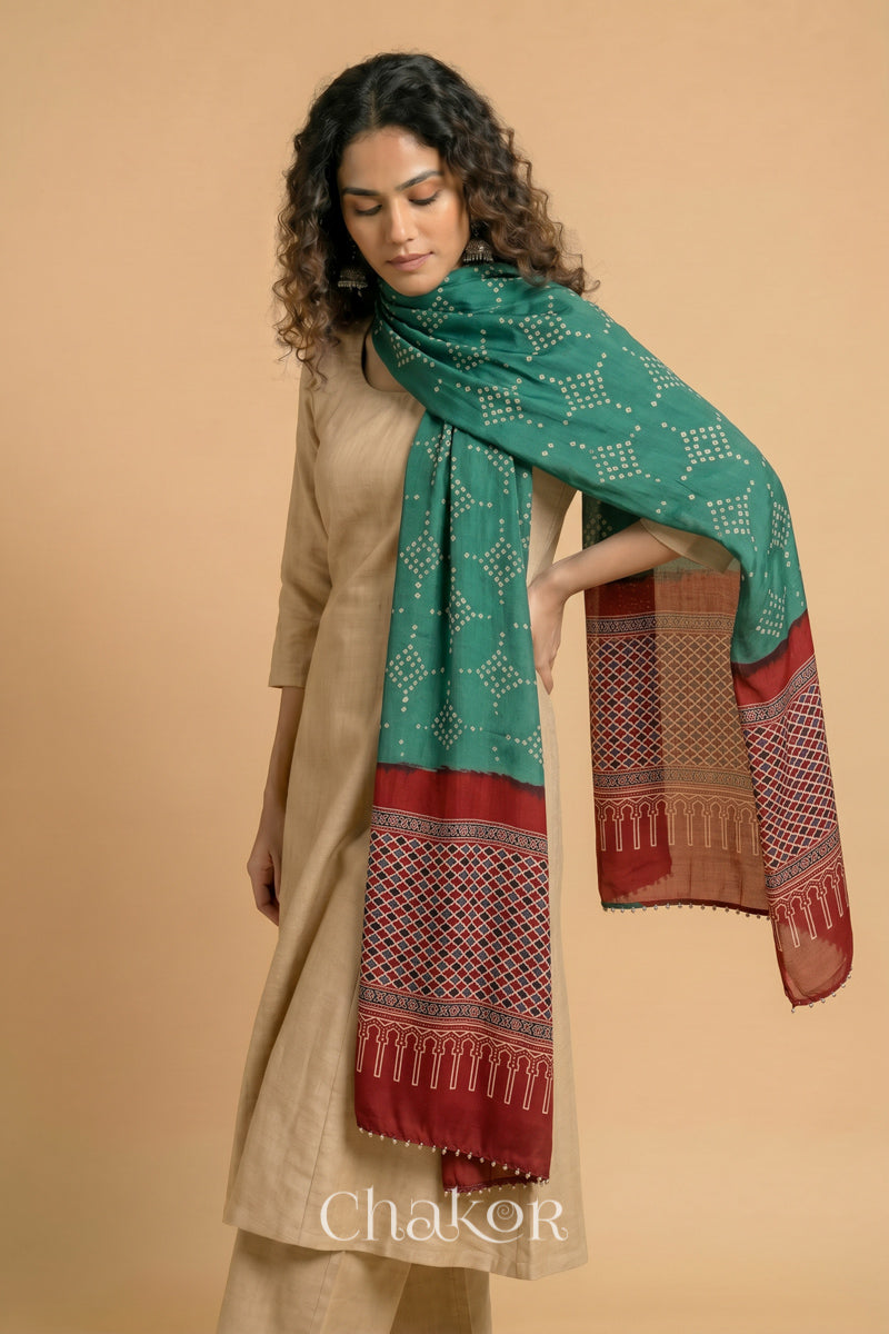 Turtle Green Bandhani modal stole styled across shoulders with detailed Madder Red Ajrakh pallu and traditional hand tied pattern.
