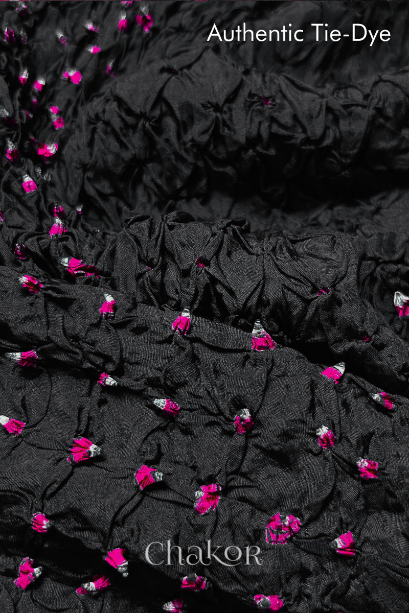 Close-up of Black mulberry silk fabric with Pink and white patterns, featuring texture of authentic bandhani patterns.

