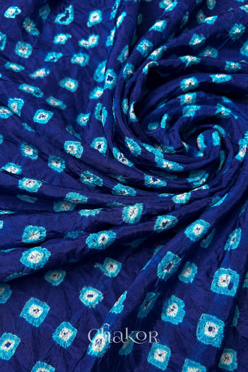 Navy Mulberry silk fabric with dual colour Turquoise Blue bandhani dots, arranged in a swirling design  & Chakor brand watermark.
