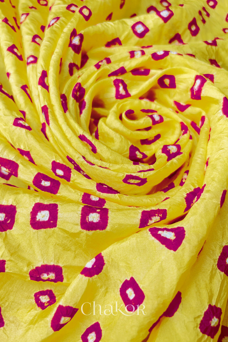 Yellow Pink Mulberry silk fabric with dual colour Pink bandhani dots, arranged in a swirling design  & Chakor brand watermark.

