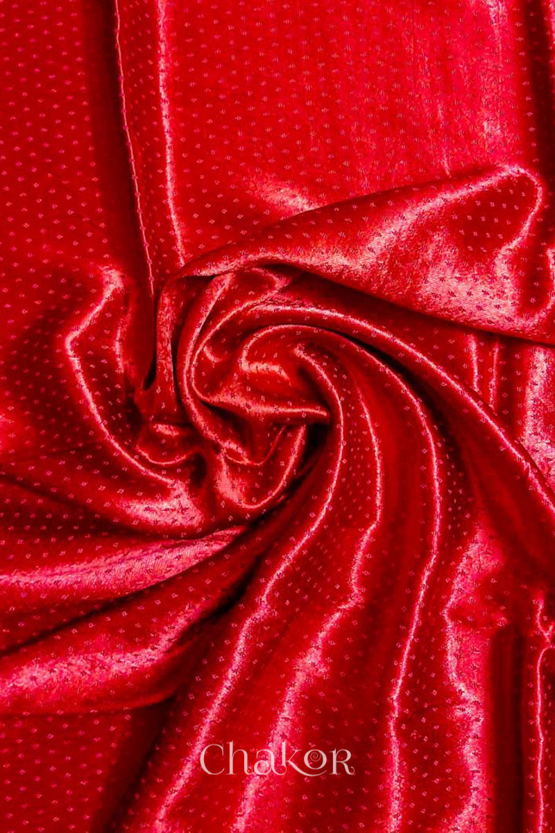 Close up of Red  Mashru Blouse Fabric with self woven design and silky texture, place is swirling drape.