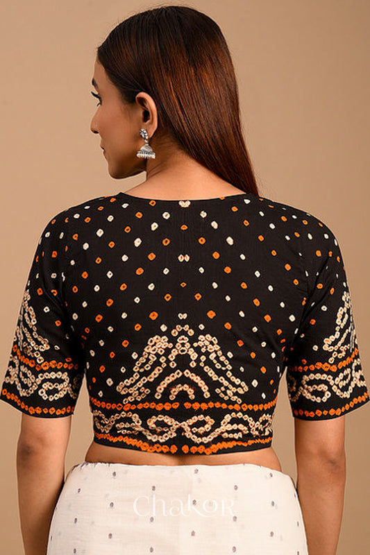 Woman wearing a handcrafted purple bandhani cotton blouse with intricate parrot motifs and boria buttons on front.