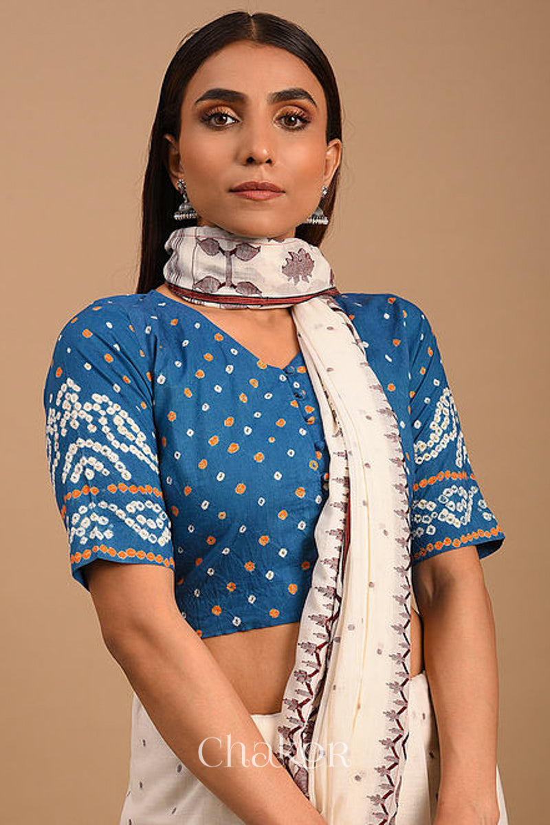 Woman wearing a handcrafted indigo blue bandhani cotton blouse with intricate parrot motifs and boria buttons on front.