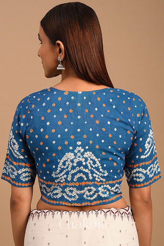 Woman wearing a handcrafted indigo blue bandhani cotton blouse with intricate parrot motifs and boria buttons on front.