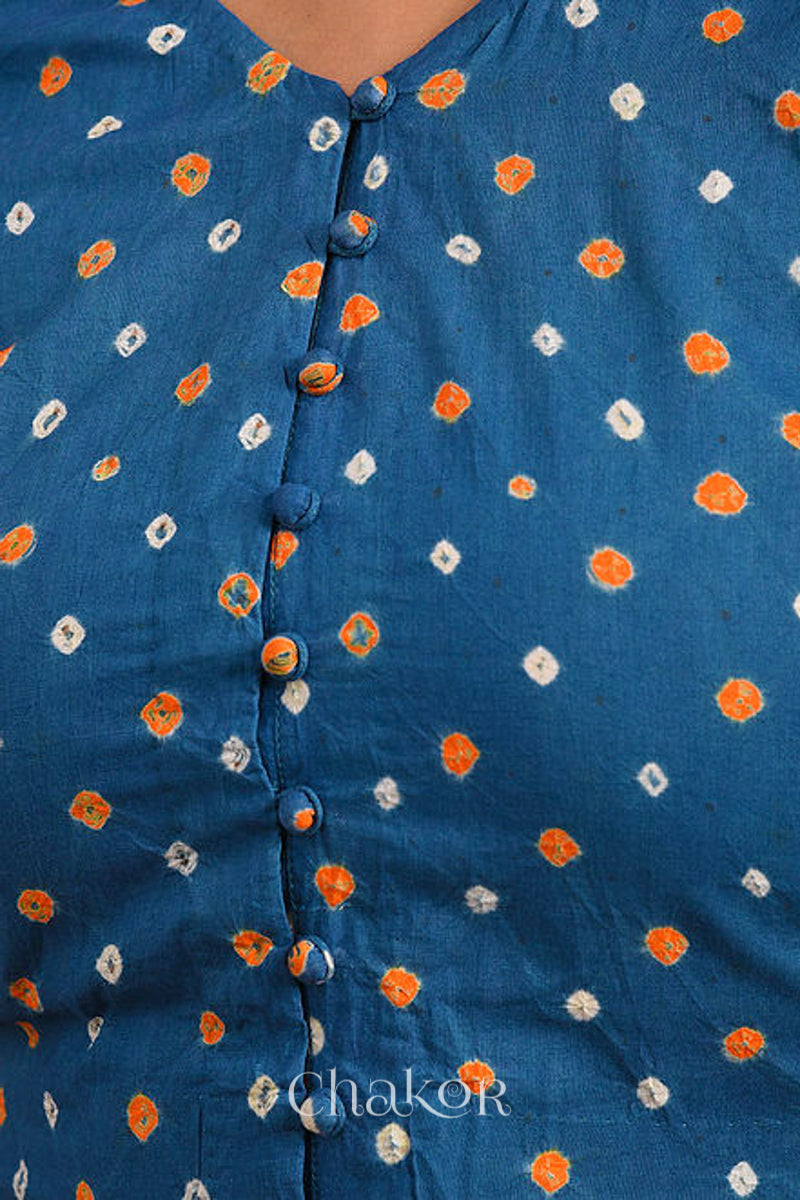 Woman wearing a handcrafted indigo blue bandhani cotton blouse with intricate parrot motifs and boria buttons on front.