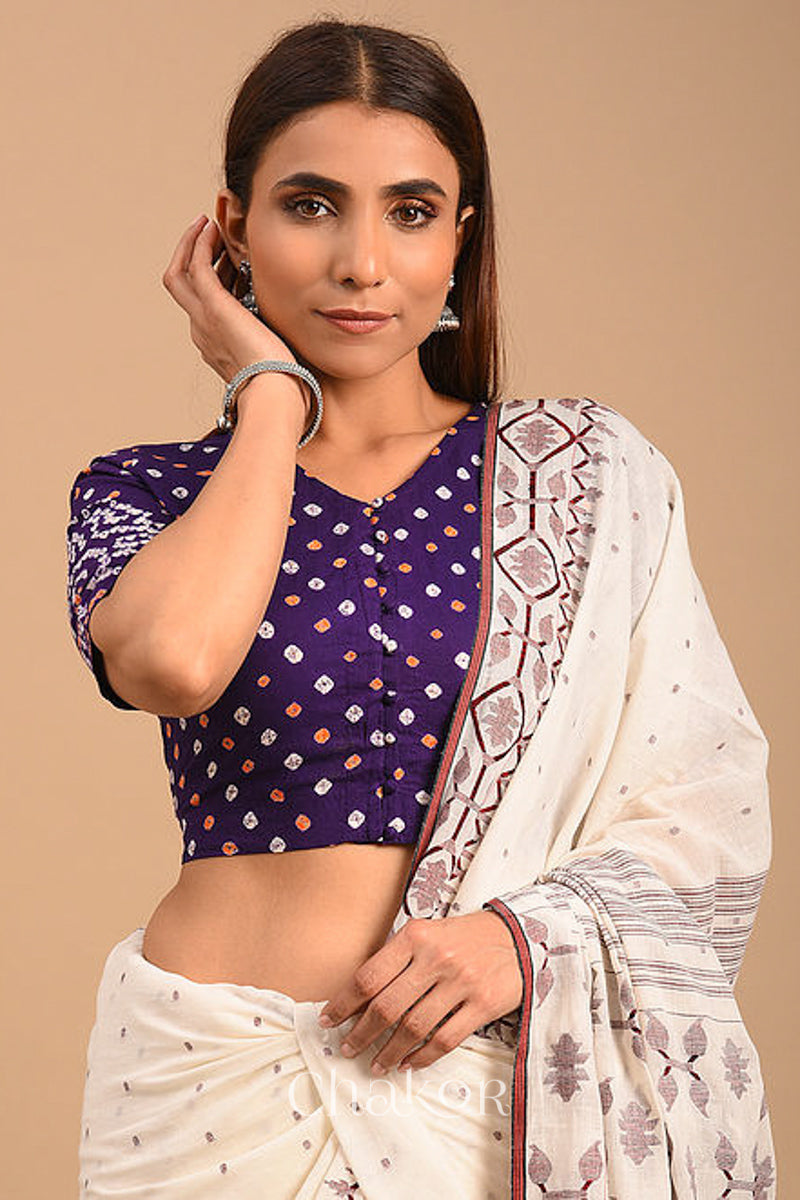 Woman wearing a handcrafted purple bandhani cotton blouse with intricate parrot motifs and boria buttons on front.