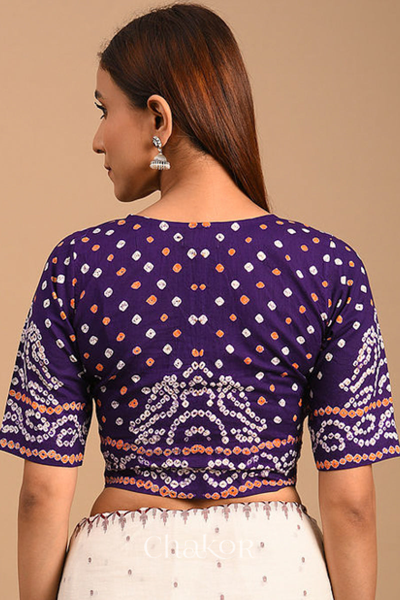 Woman wearing a handcrafted purple bandhani cotton blouse with intricate parrot motifs and boria buttons on front.