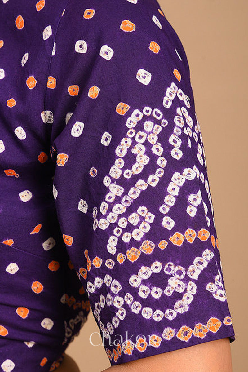 Woman wearing a handcrafted purple bandhani cotton blouse with intricate parrot motifs and boria buttons on front.