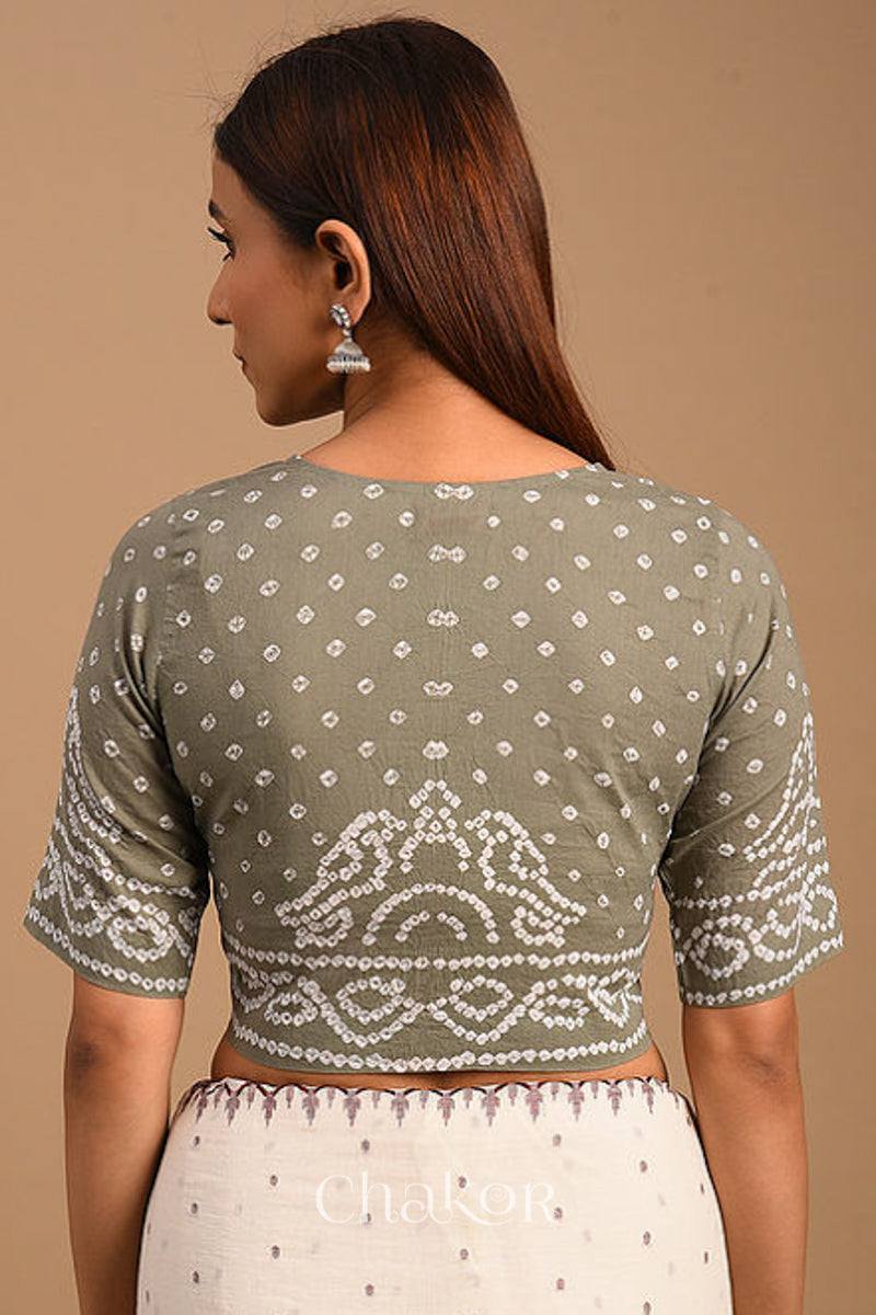 Woman wearing a handcrafted grey bandhani cotton blouse with intricate parrot motifs and boria buttons on front.